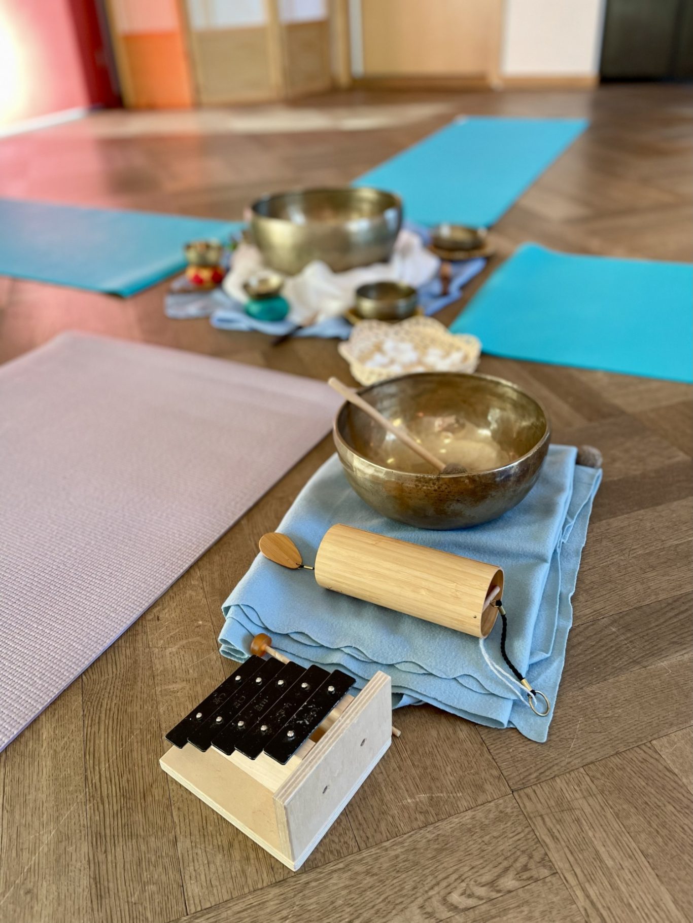 Klanginstrumente Trommeln, Klangschalen und Yoga-Matten auf dem Boden in einem ruhigen Raum.