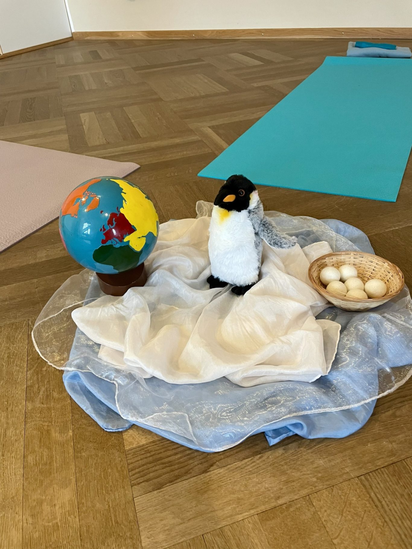 Antarktis-Reise mit dem kleinen Pinguin Eine Weltkugel, ein Pinguin und ein Korb mit Eiern auf einer Decke.