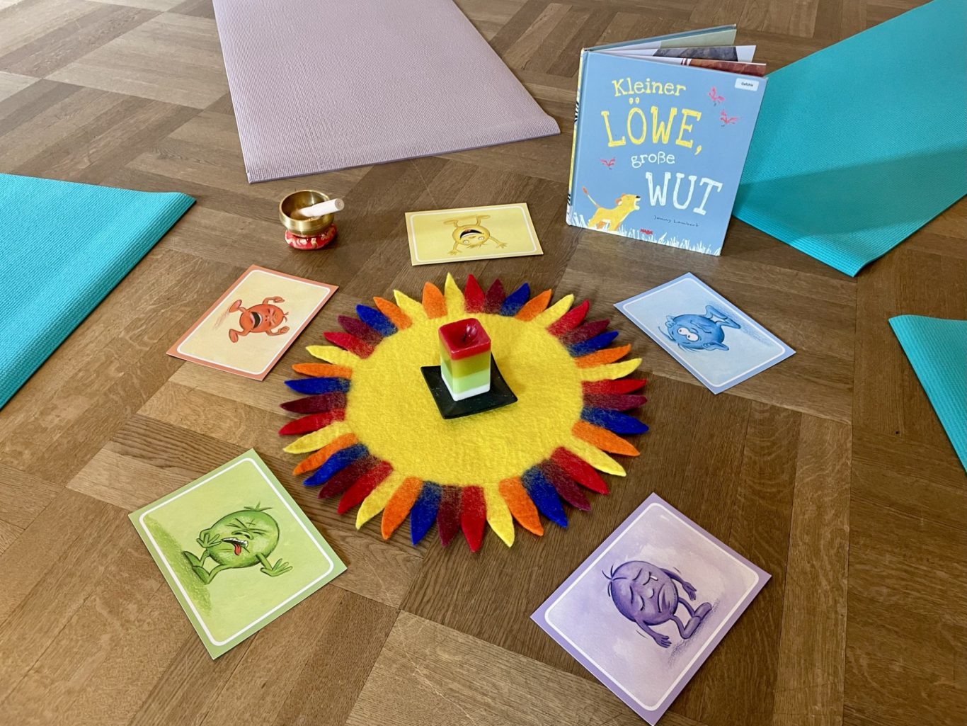 Thema Gefühle/Wut Bunte Anordnung von Yogakarten, einem Spielzeug und Zeichnungen in der Kreismitte des Yogaraumes.