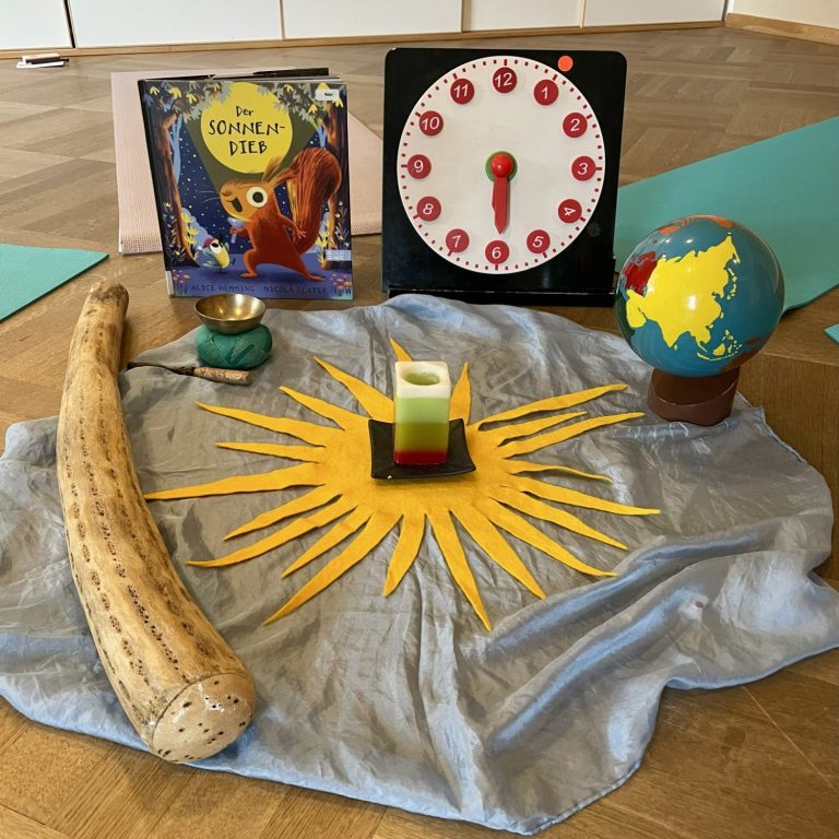 Kreismitte mit Buch, Uhr, Globus, Kerze und dekorativen Elementen in einem hellen Raum.