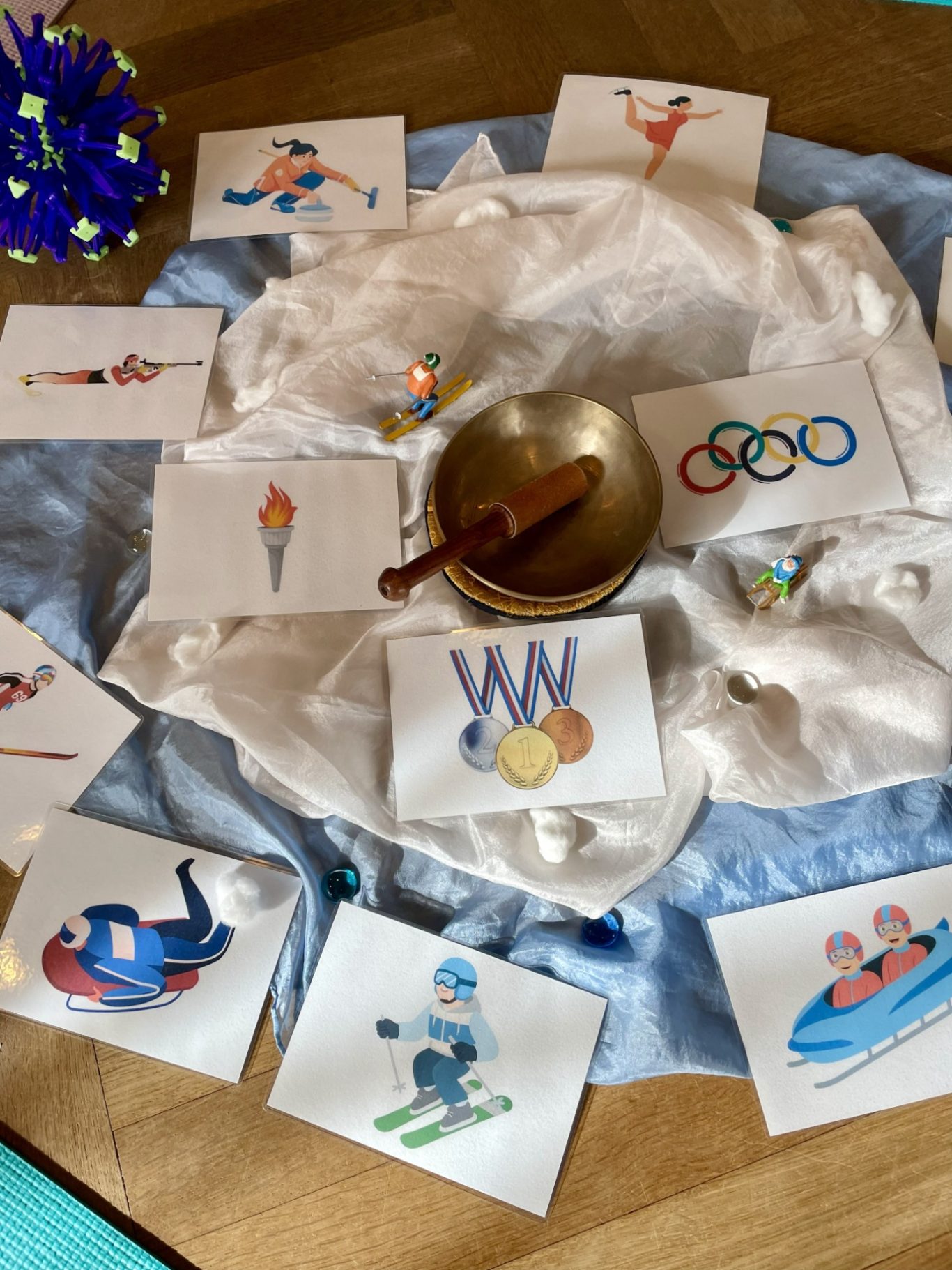 Winterolympiade Olympische Symbole und Sportlerillustrationen auf einem dekorierten Tisch.