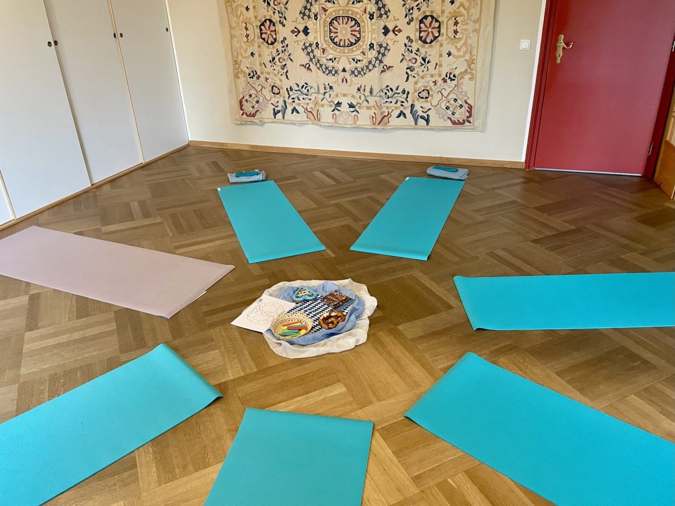 Der Yogaraum Sechs Yogamatten in einem Raum mit hölzernem Boden und einer dekorativen Wandgestaltung.